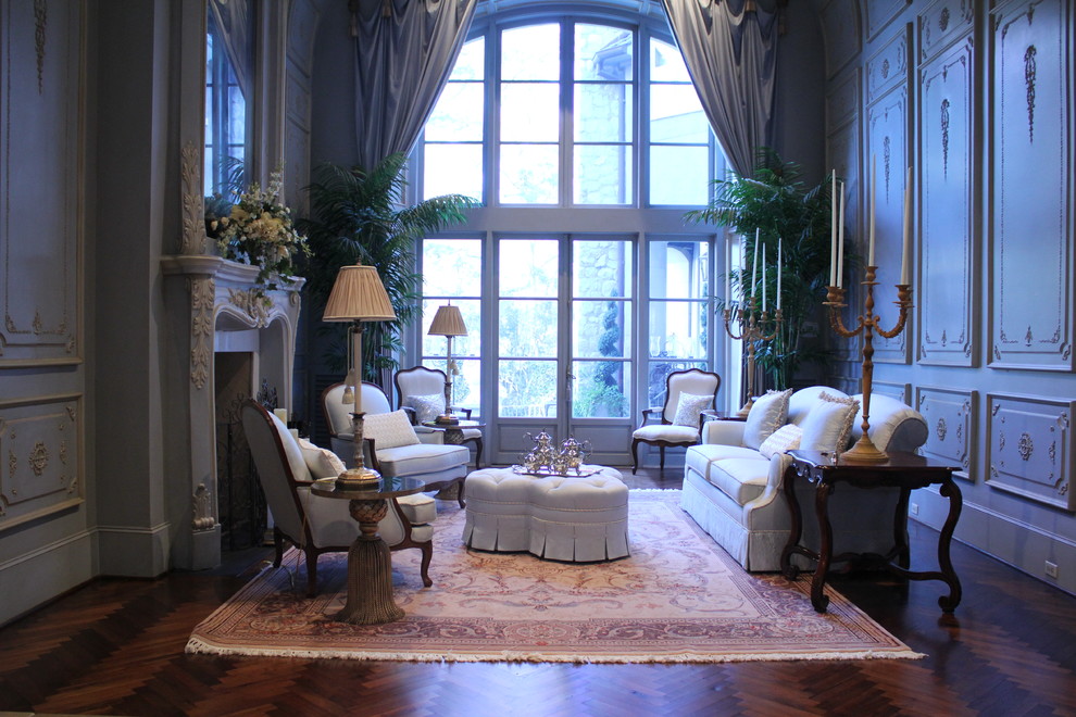 Example of a large tuscan formal medium tone wood floor living room design in Houston with blue walls, a standard fireplace, a plaster fireplace and no tv