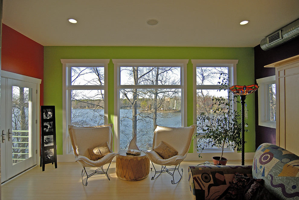 Foto de salón abierto bohemio de tamaño medio con paredes verdes, suelo de madera clara, todas las chimeneas y marco de chimenea de metal