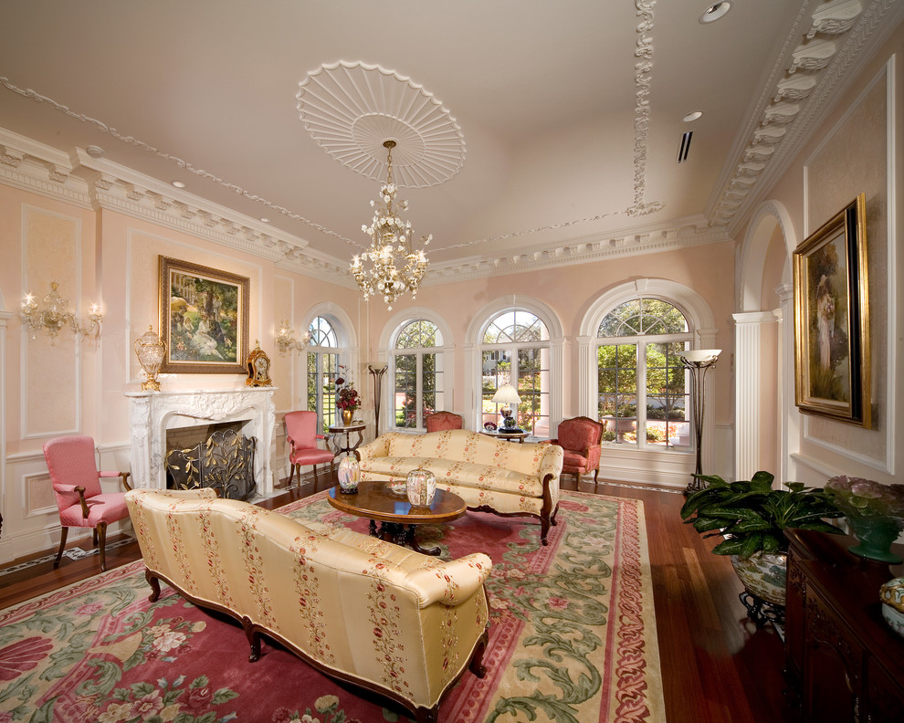 Inspiration för klassiska vardagsrum, med rosa väggar, mörkt trägolv och en standard öppen spis