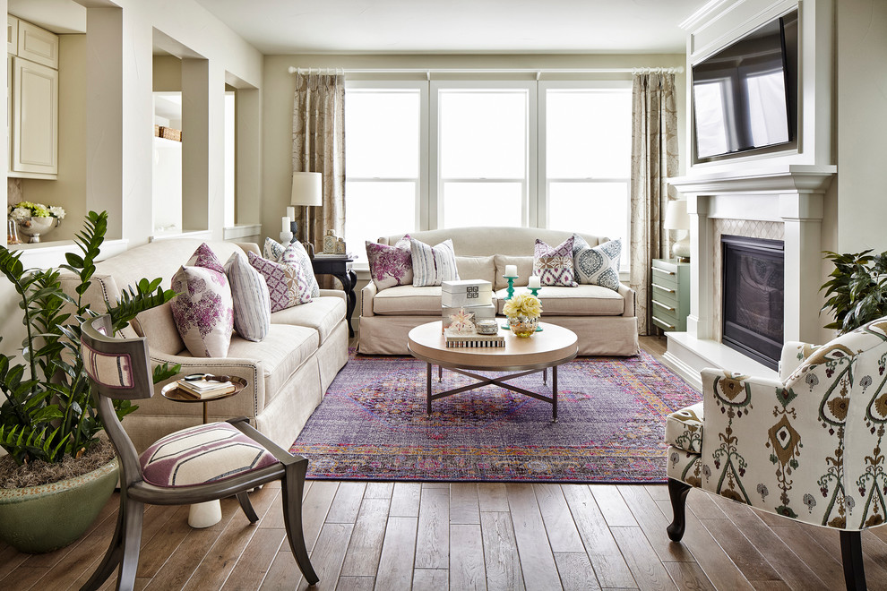 Klassisches Wohnzimmer mit beiger Wandfarbe, braunem Holzboden, Kamin, gefliester Kaminumrandung und TV-Wand in Denver