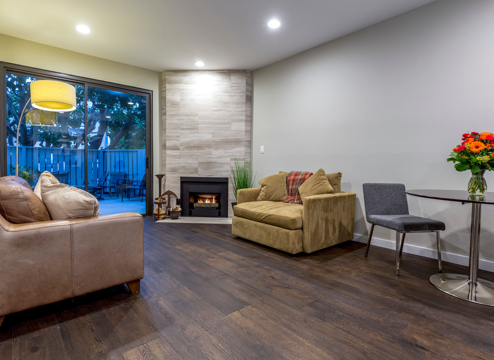 Medium sized traditional open plan living room in Los Angeles with dark hardwood flooring, a standard fireplace, a stone fireplace surround, grey walls and brown floors.