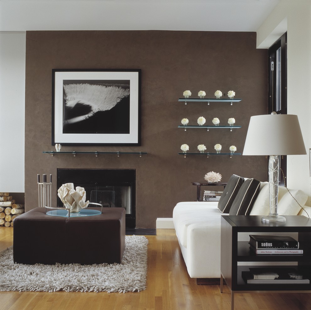 Diseño de salón actual con paredes marrones, suelo de madera clara, todas las chimeneas y marco de chimenea de yeso