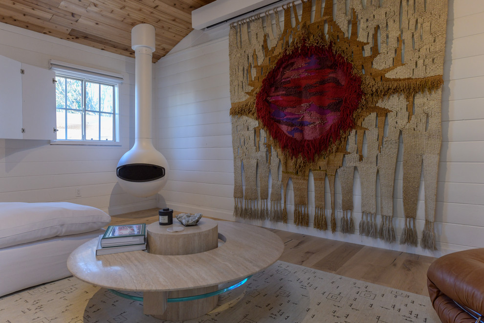 Foto de salón abierto marinero con paredes blancas, suelo de madera clara, chimeneas suspendidas, televisor retractable y suelo beige