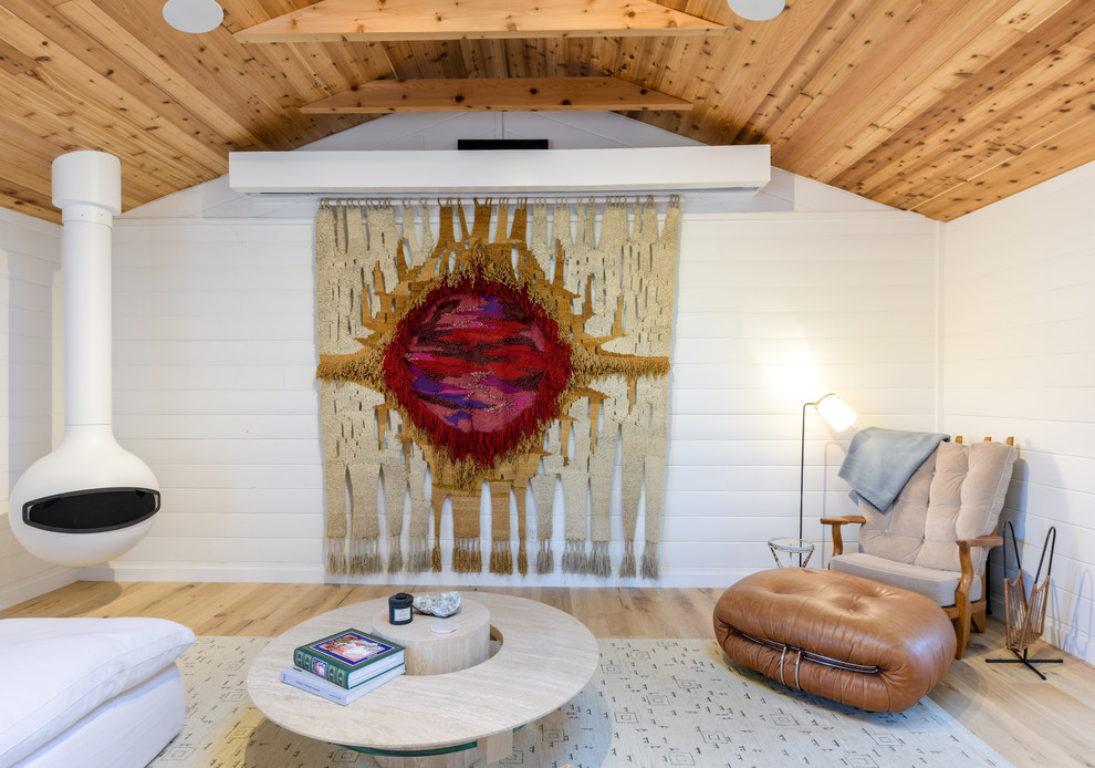 Immagine di un soggiorno stile marinaro aperto con pareti bianche, parquet chiaro, camino sospeso, TV nascosta e pavimento beige