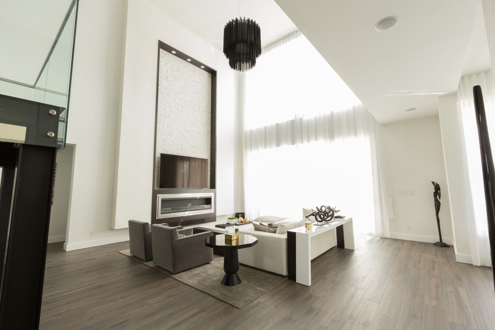 Aménagement d'un grand salon mansardé ou avec mezzanine moderne avec une salle de réception, un mur blanc, un sol en bois brun, une cheminée ribbon et un manteau de cheminée en métal.