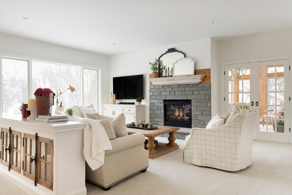 Idée de décoration pour un salon champêtre ouvert avec un mur blanc, moquette, une cheminée standard, un manteau de cheminée en pierre et un sol beige.