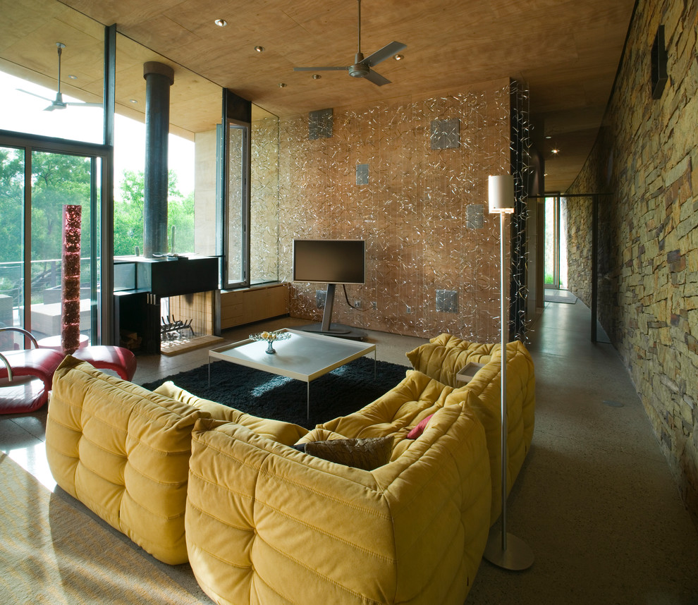 Idées déco pour un salon moderne avec une cheminée double-face, un téléviseur indépendant et un mur en pierre.