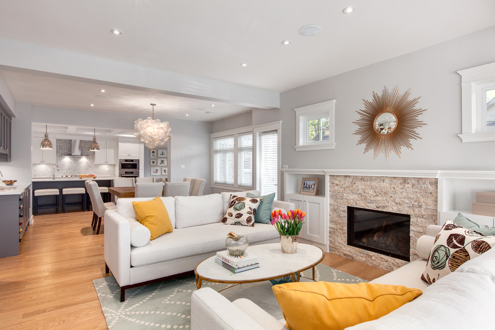 This is an example of a large classic formal open plan living room in Vancouver with grey walls, medium hardwood flooring, a standard fireplace, a stone fireplace surround, no tv and brown floors.