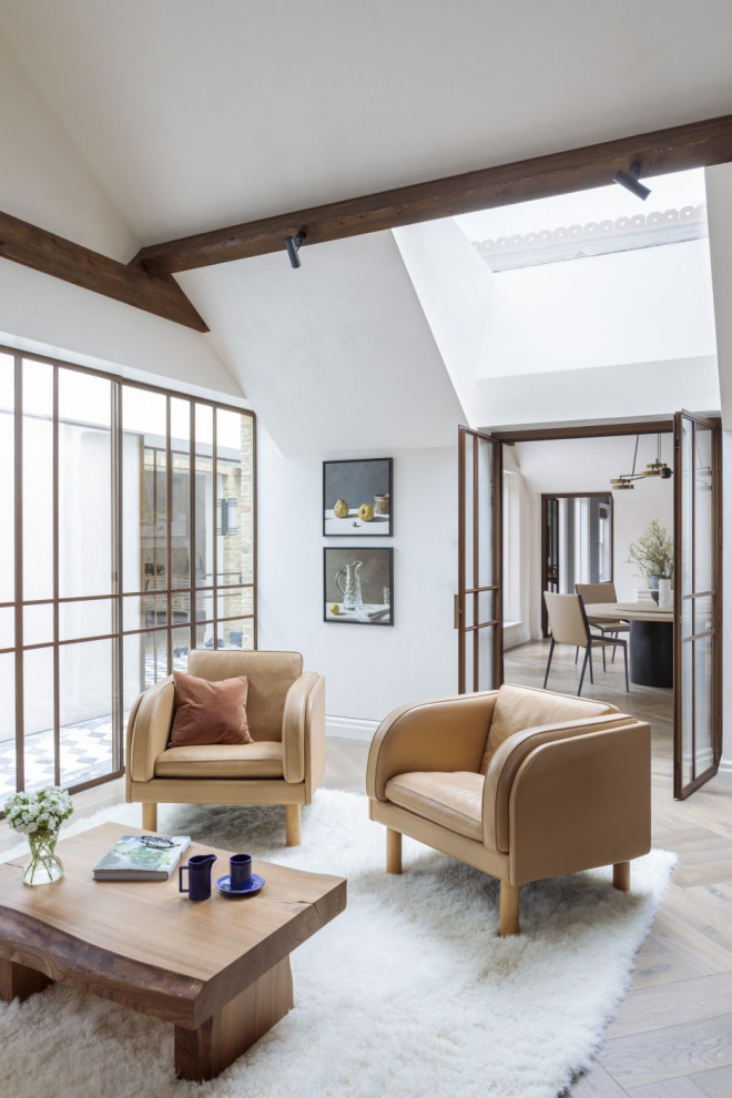 Abgetrenntes Modernes Wohnzimmer mit weißer Wandfarbe, braunem Holzboden, braunem Boden, freigelegten Dachbalken und gewölbter Decke in Sonstige