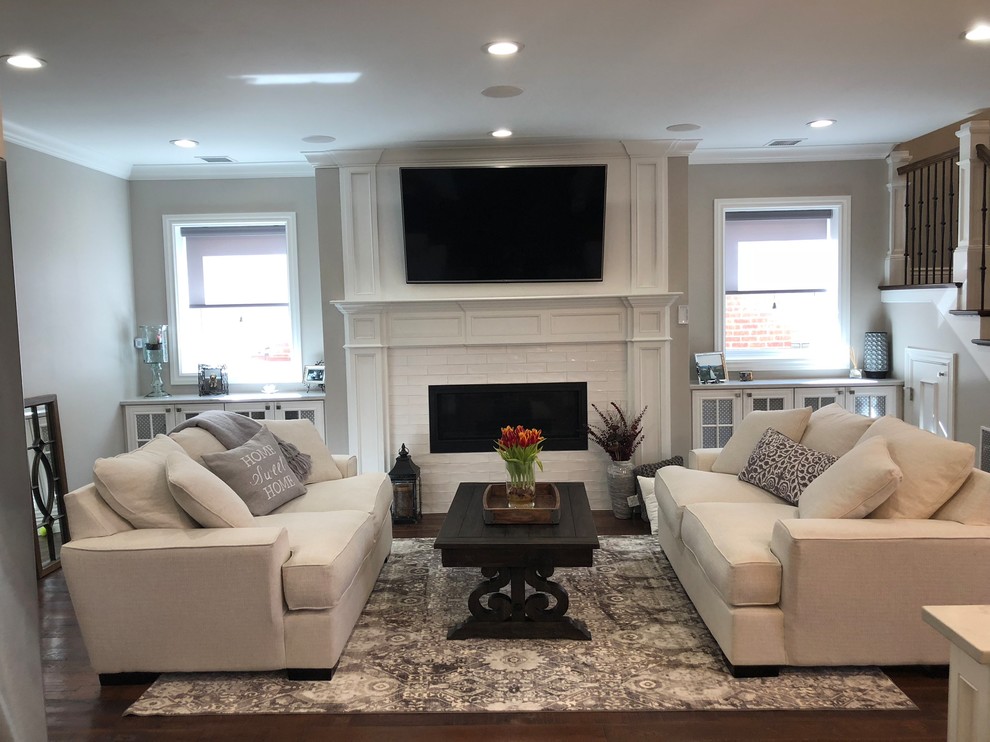 Example of a large classic formal and open concept medium tone wood floor and brown floor living room design in Denver with gray walls, a ribbon fireplace, a brick fireplace and a wall-mounted tv