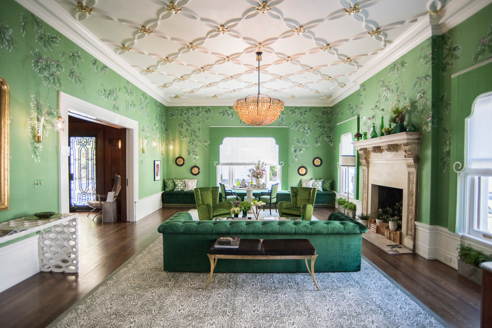 Modelo de salón para visitas cerrado bohemio con paredes verdes, suelo de madera oscura, todas las chimeneas y marco de chimenea de piedra