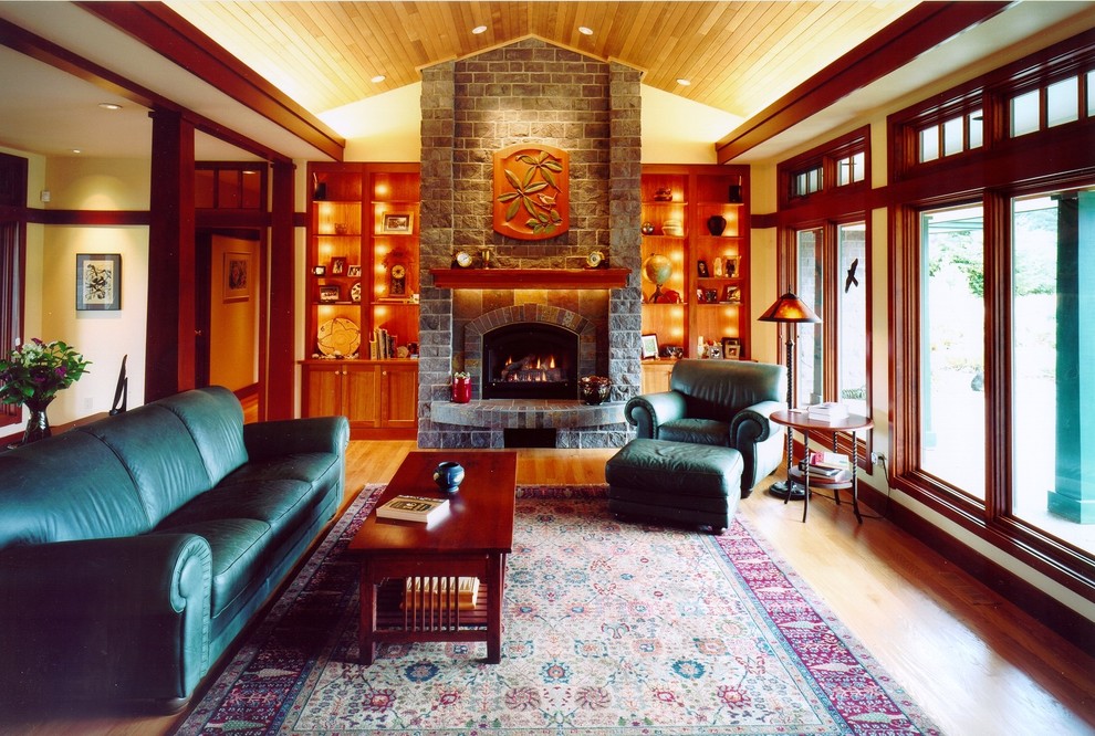 Ejemplo de salón abierto de estilo americano grande con suelo de madera clara, estufa de leña, marco de chimenea de piedra y paredes beige