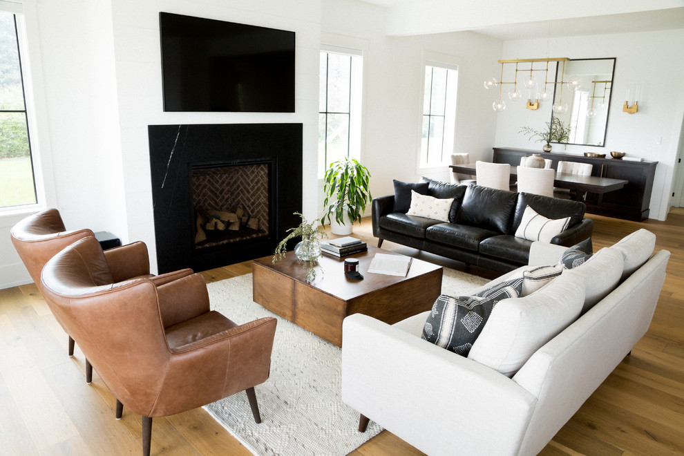 Large classic open plan living room in Toronto with white walls, light hardwood flooring, a standard fireplace, a stone fireplace surround, a wall mounted tv and brown floors.