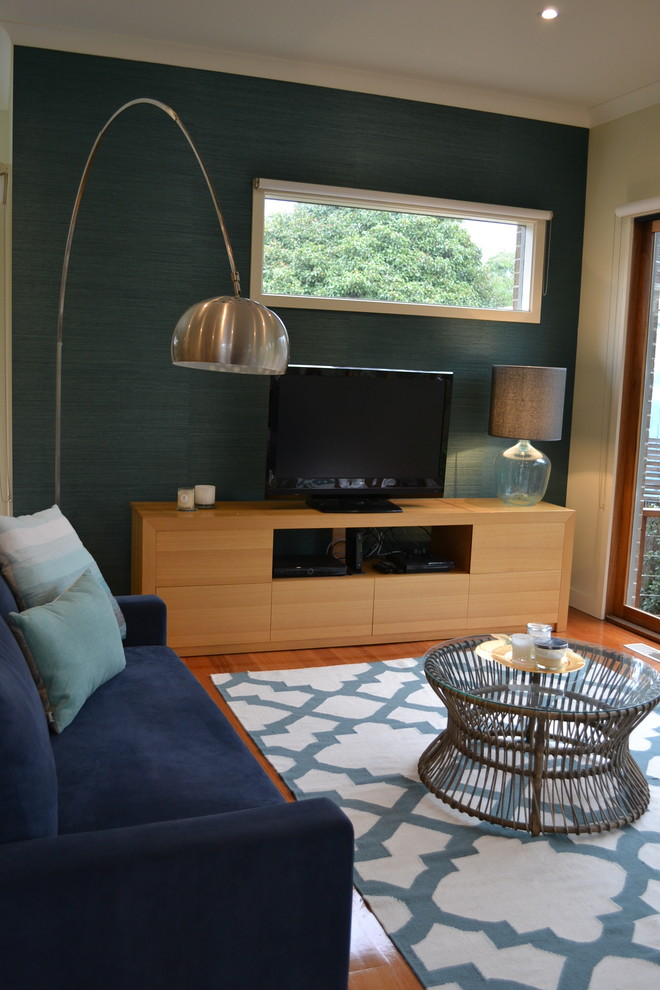 Cette image montre un salon design de taille moyenne avec une salle de réception, un mur bleu, un sol en bois brun et un téléviseur indépendant.