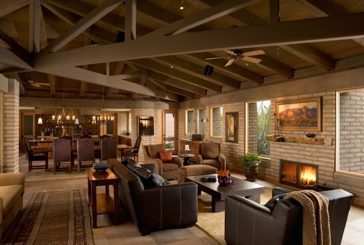 Exemple d'un grand salon sud-ouest américain ouvert avec un mur beige, une cheminée standard, un manteau de cheminée en brique, aucun téléviseur, sol en béton ciré et un sol multicolore.