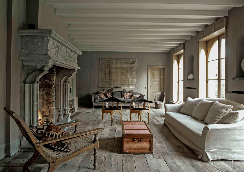 Geräumiges, Fernseherloses, Offenes Shabby-Style Wohnzimmer mit grauer Wandfarbe, braunem Holzboden, Kamin und Kaminumrandung aus Stein in Sonstige
