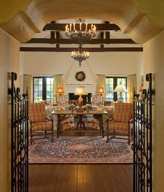 Example of a mid-sized tuscan enclosed and formal dark wood floor and brown floor living room design in San Diego with beige walls, a standard fireplace, a wood fireplace surround and no tv