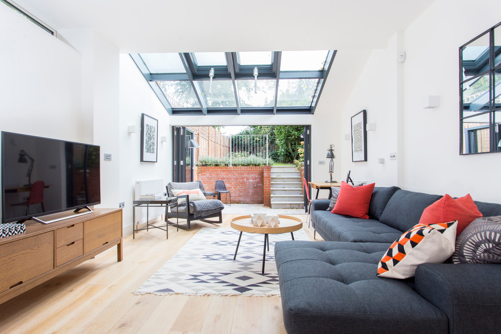 Foto di un soggiorno contemporaneo di medie dimensioni e chiuso con pareti bianche, TV autoportante, pavimento beige e parquet chiaro