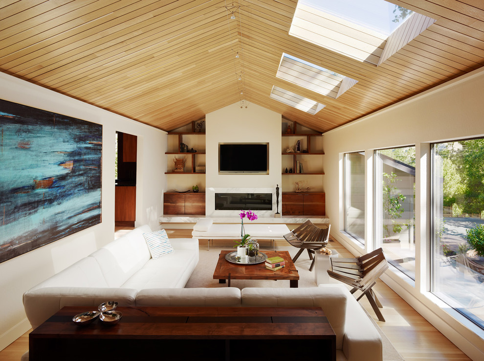 Idéer för ett modernt vardagsrum, med beige väggar, en bred öppen spis och en väggmonterad TV