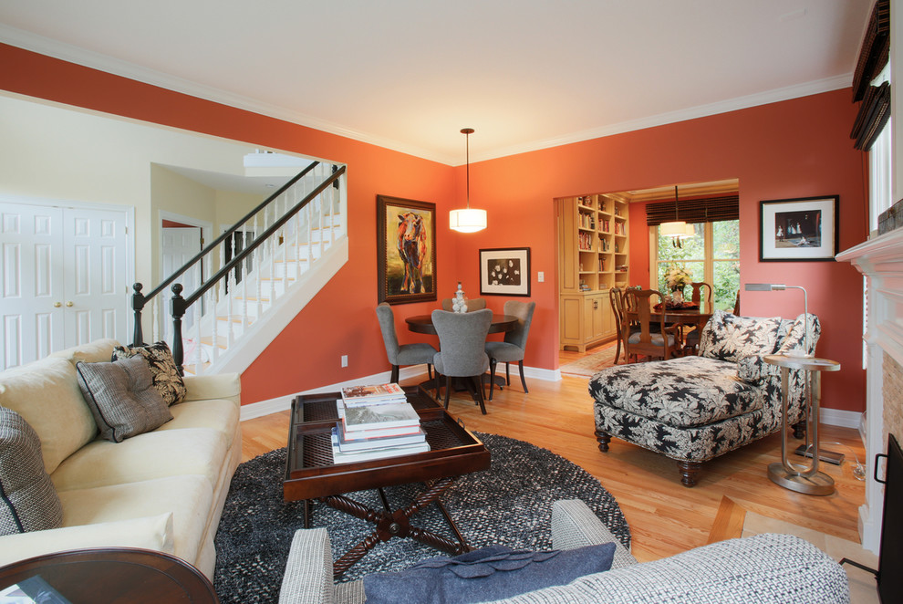 Inspiration pour un grand salon traditionnel fermé avec un mur orange, parquet clair, une cheminée standard et un manteau de cheminée en pierre.