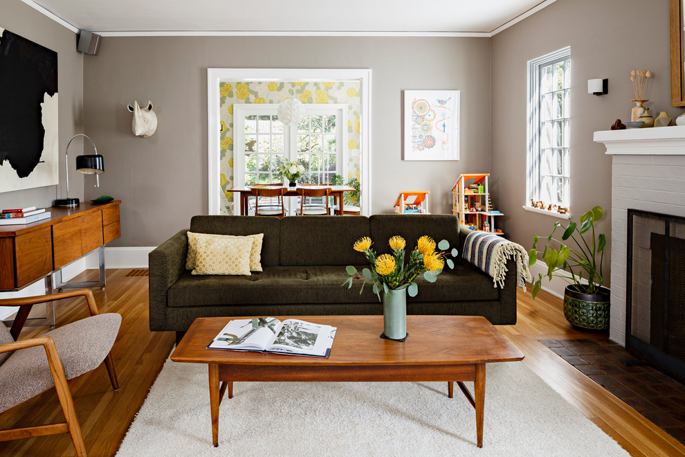 Idée de décoration pour un salon design de taille moyenne et fermé avec un mur gris, un sol en bois brun, un manteau de cheminée en brique et une cheminée standard.