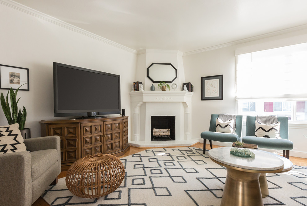 Idee per un soggiorno classico con pareti bianche, pavimento in legno massello medio, camino classico, TV autoportante e pavimento marrone