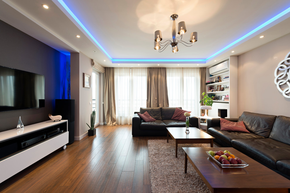 Стильный дизайн: большая парадная, изолированная гостиная комната в стиле модернизм с бежевым полом, серыми стенами, темным паркетным полом и телевизором на стене без камина - последний тренд