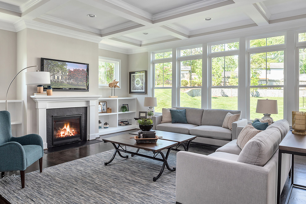 Traditional grey and teal living room in DC Metro with beige walls, dark hardwood flooring, a standard fireplace, a wall mounted tv and brown floors.