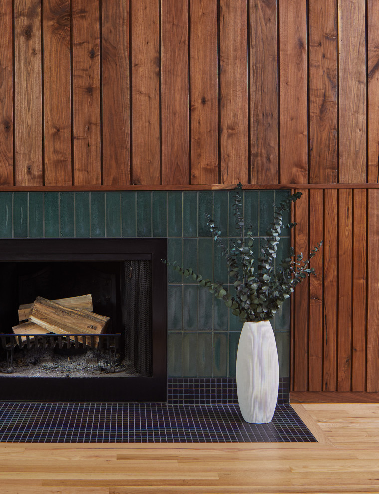 Aménagement d'un salon rétro avec parquet clair, une cheminée standard et un manteau de cheminée en carrelage.