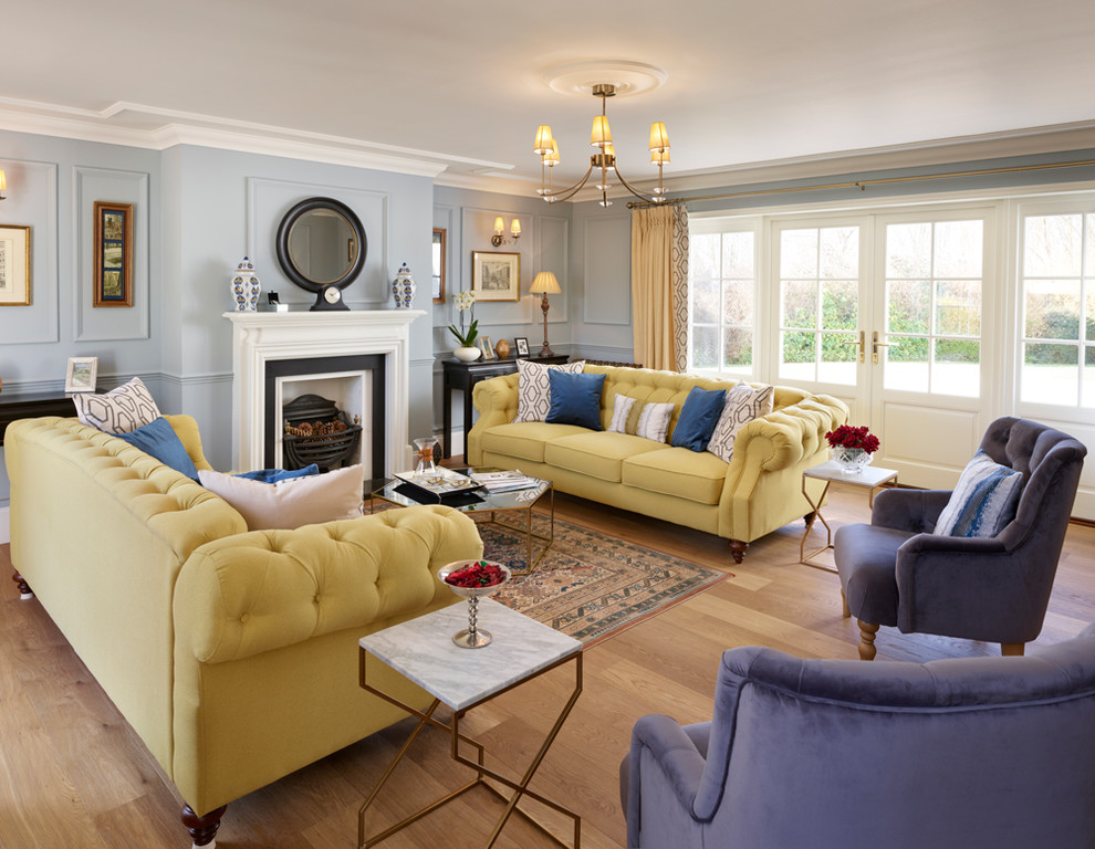 Foto di un soggiorno chic di medie dimensioni con sala formale, pareti blu, camino classico e pavimento in legno massello medio