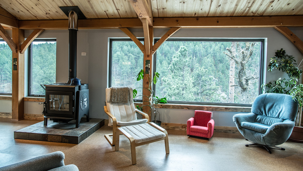 На фото: открытая гостиная комната среднего размера в современном стиле с серыми стенами, пробковым полом, печью-буржуйкой и телевизором на стене с