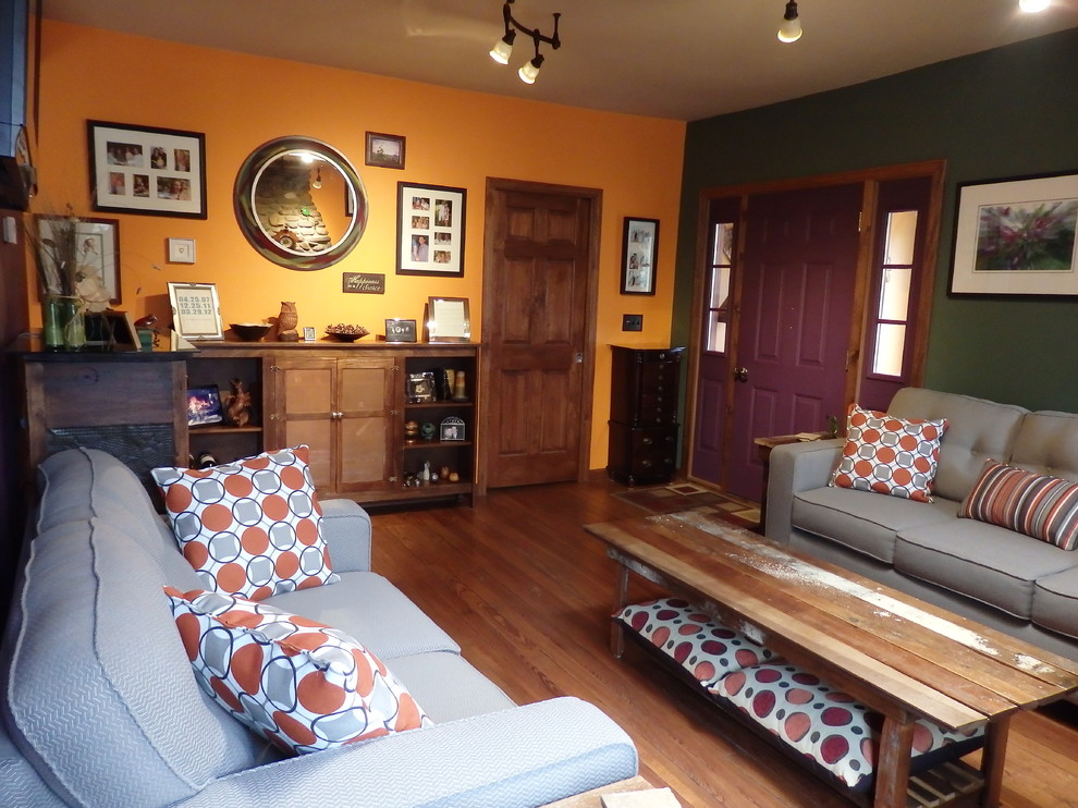 Exemple d'un petit salon éclectique fermé avec une salle de réception, un mur multicolore, un sol en bois brun, une cheminée double-face, un manteau de cheminée en pierre et un téléviseur fixé au mur.