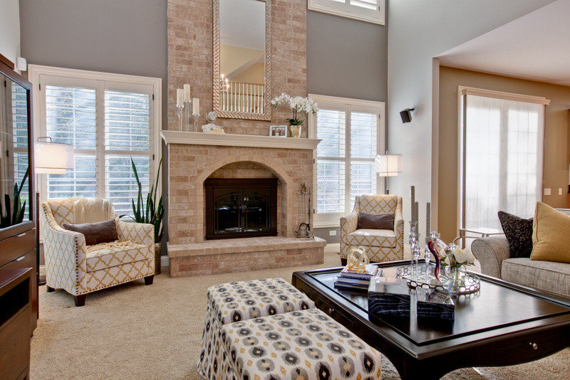 На фото: открытая гостиная комната среднего размера в стиле неоклассика (современная классика) с серыми стенами, ковровым покрытием, стандартным камином, фасадом камина из кирпича и скрытым телевизором