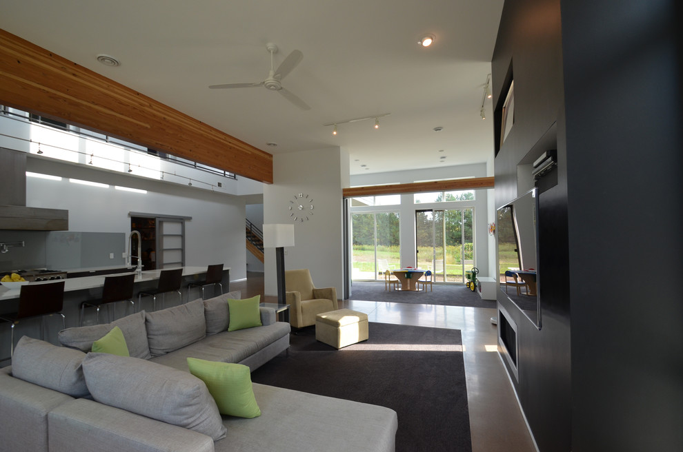 Imagen de salón abierto minimalista grande con paredes blancas, suelo de cemento, chimenea lineal, marco de chimenea de yeso y pared multimedia