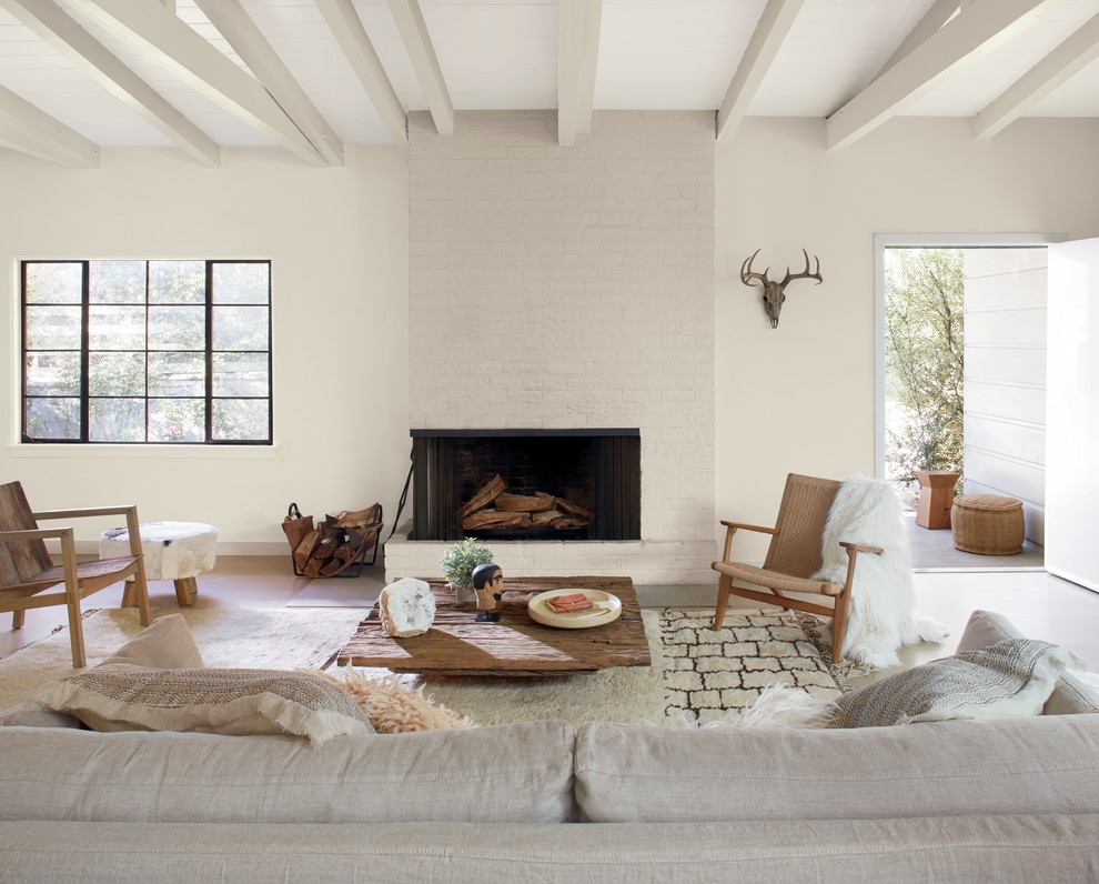 Exemple d'un grand salon sud-ouest américain avec un mur blanc, une cheminée standard, un manteau de cheminée en brique et aucun téléviseur.