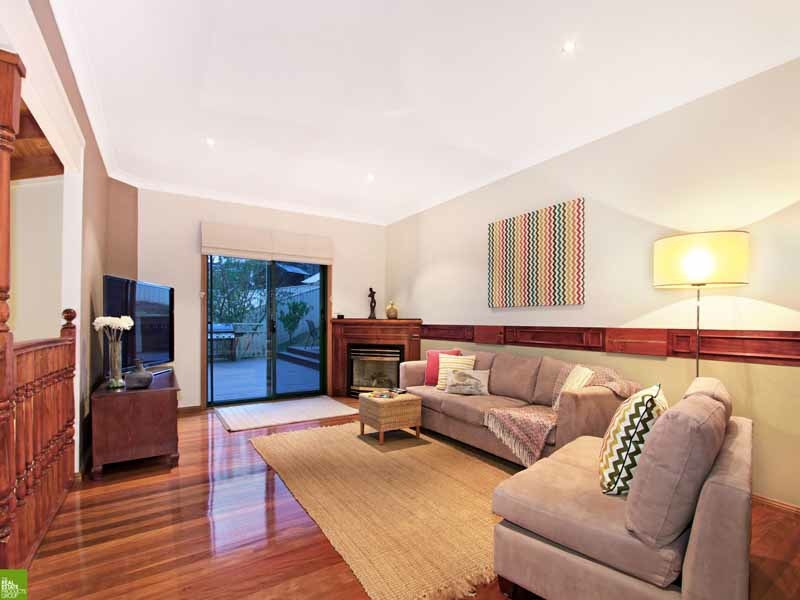 Example of a beach style medium tone wood floor living room design in Wollongong with beige walls, a corner fireplace and a wood fireplace surround