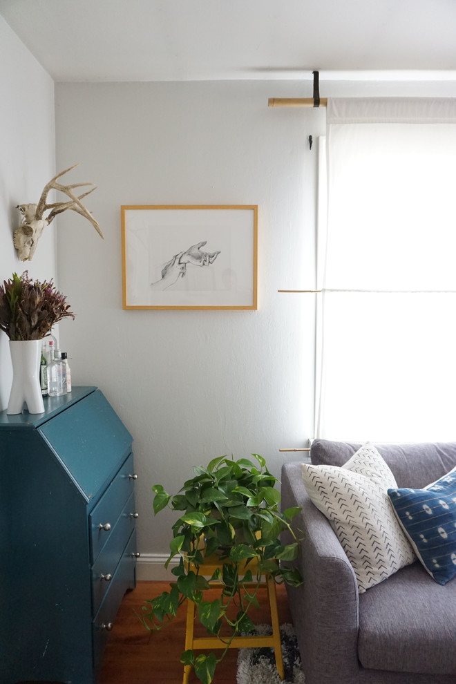 Foto på ett mellanstort eklektiskt separat vardagsrum, med ett finrum, vita väggar, ljust trägolv och en fristående TV