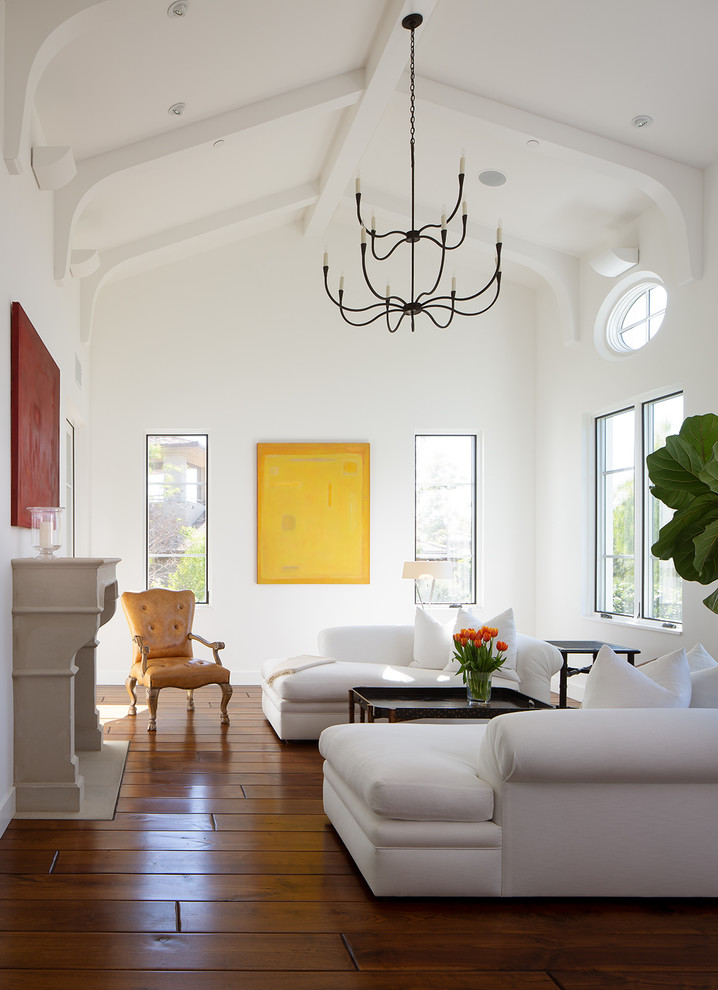 На фото: гостиная комната в средиземноморском стиле с белыми стенами, паркетным полом среднего тона, стандартным камином и коричневым полом
