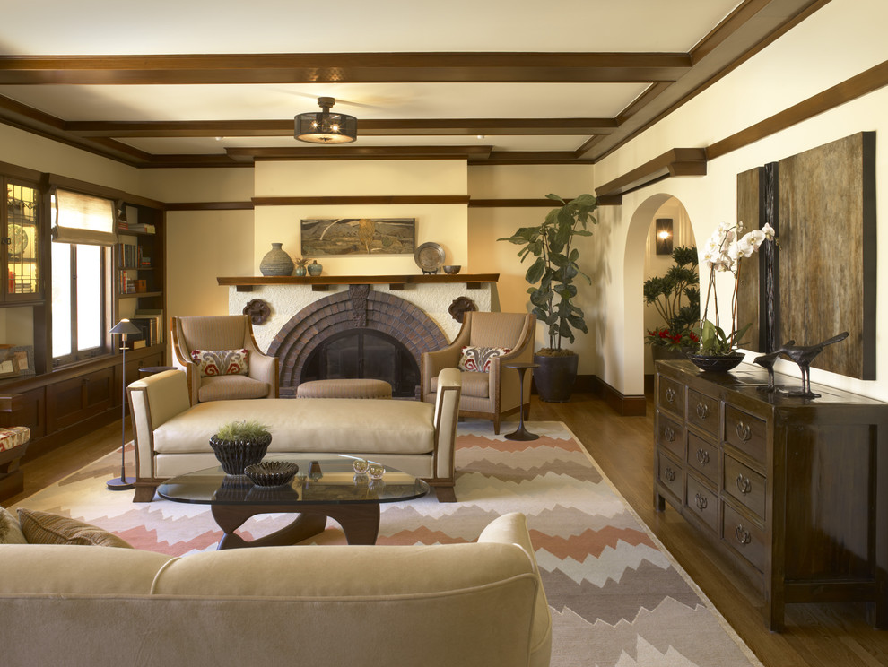 Idéer för ett amerikanskt separat vardagsrum, med en spiselkrans i tegelsten, beige väggar, mellanmörkt trägolv, en standard öppen spis och brunt golv