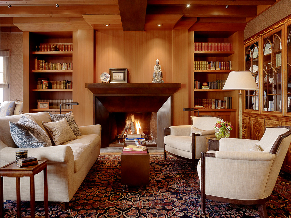 Cette photo montre un grand salon chic fermé avec une bibliothèque ou un coin lecture, une cheminée standard, un mur marron, un sol en bois brun, un manteau de cheminée en métal et aucun téléviseur.