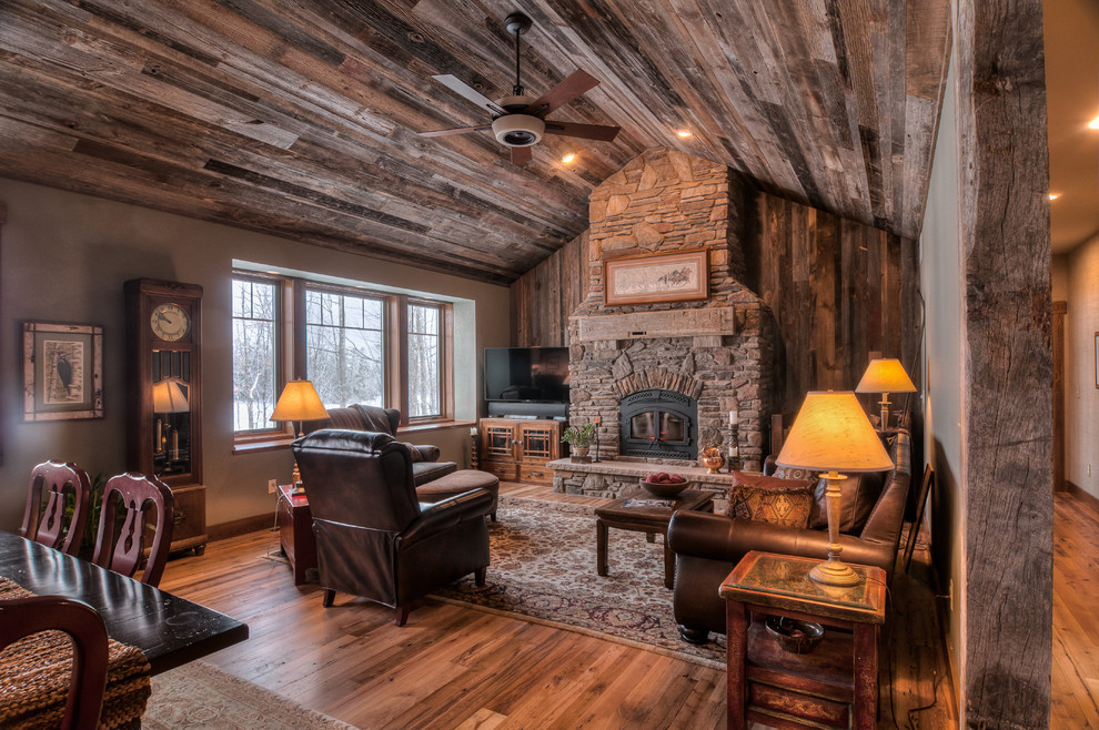 Country living room in Other with a wood burning stove and a stone fireplace surround.