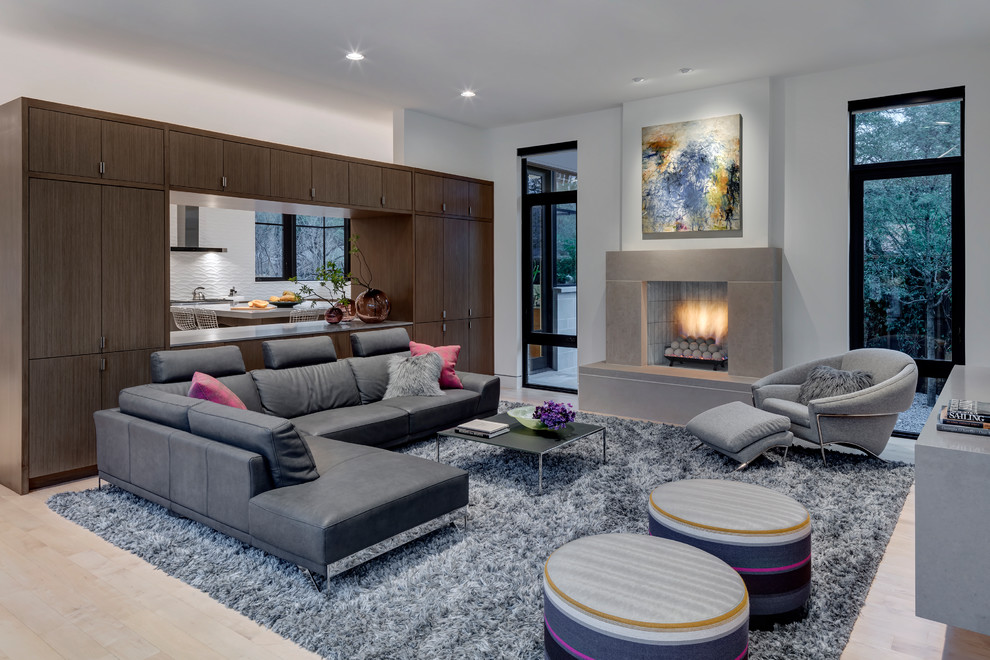 Contemporary open plan living room in Dallas with white walls, light hardwood flooring, a standard fireplace and beige floors.