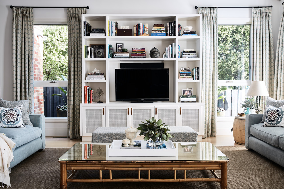Photo of a living room in Melbourne with white walls, light hardwood flooring and a built-in media unit.