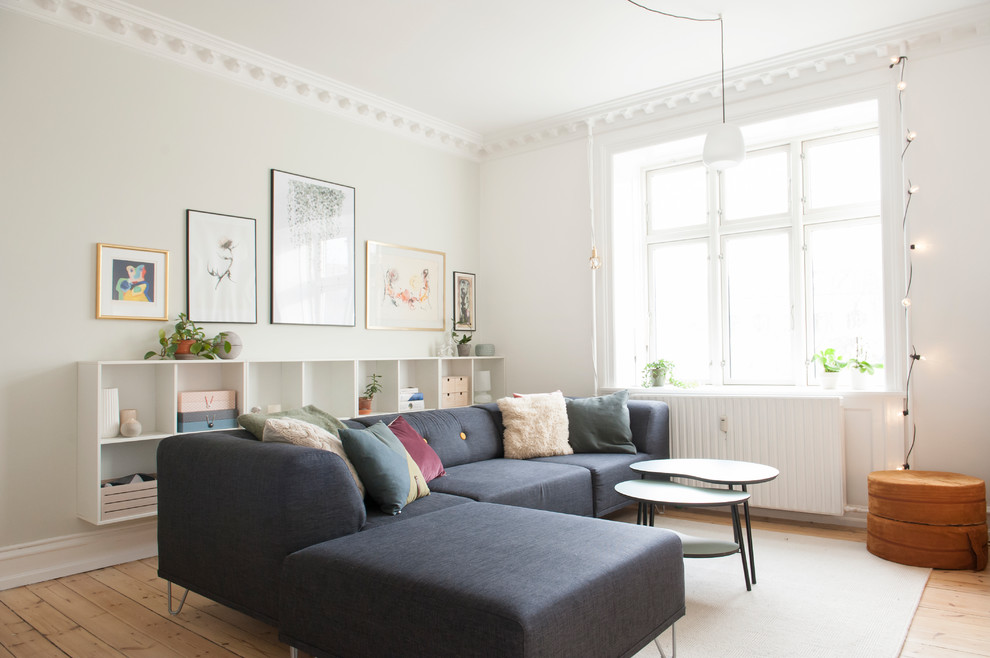 Example of a danish medium tone wood floor and brown floor living room design in Los Angeles with white walls