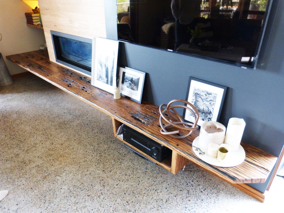 ニューカッスルにある中くらいなコンテンポラリースタイルのおしゃれなリビング (コンクリートの床、薪ストーブ、木材の暖炉まわり、据え置き型テレビ) の写真