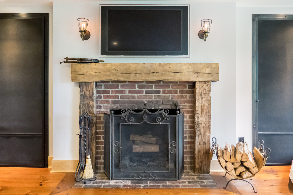 Design ideas for a medium sized rustic enclosed living room in Philadelphia with white walls, a standard fireplace, a brick fireplace surround and brown floors.