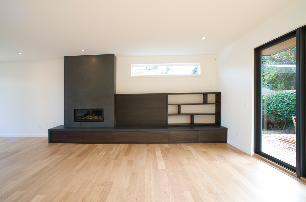 Diseño de salón abierto minimalista con todas las chimeneas, marco de chimenea de hormigón y televisor retractable