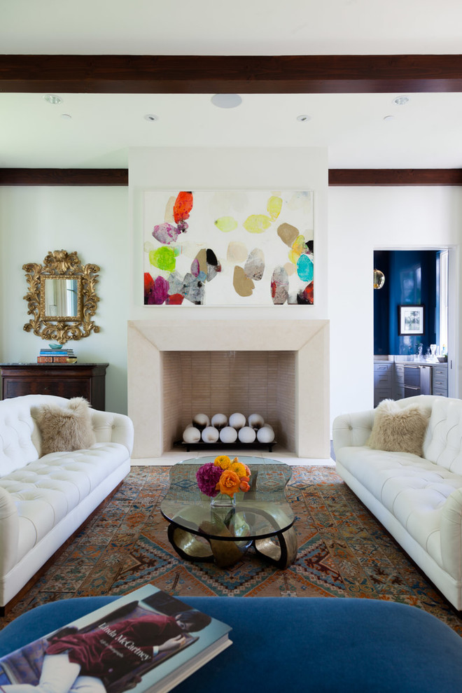 На фото: гостиная комната в стиле неоклассика (современная классика) с белыми стенами, стандартным камином и синим диваном с