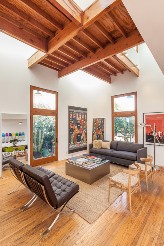 Cette image montre un salon design de taille moyenne avec un mur blanc et un sol en bois brun.