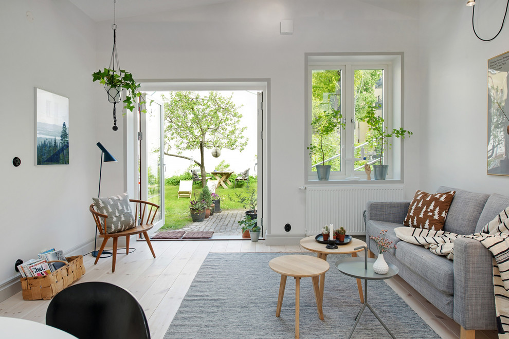 Example of a mid-sized danish open concept light wood floor living room design in Gothenburg with white walls, no fireplace and no tv